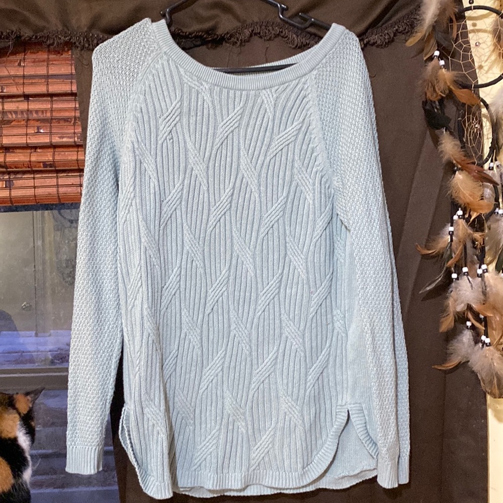 A teal sweater, with a knitted pattern